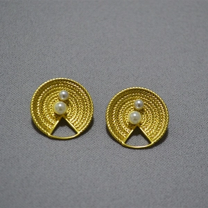 Vue détaillée des boucles d'oreilles vintage avec texture tissée et perles blanches