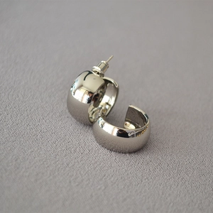 Detailed view of wide silver C-shape hoop earrings with a polished mirror finish surface