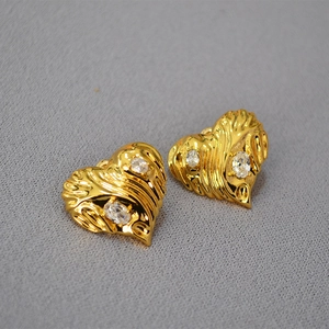 Detail of heart-shaped gold earrings with ripple texture and sparkling zircon stones
