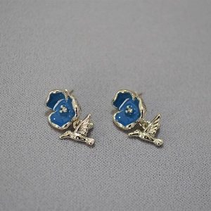 Detail of blue enamel flower and silver hummingbird earrings with intricate textures