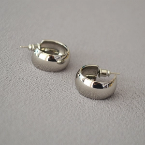 Detailed macro view of silver-toned wide C-shaped earrings with high polish mirror finish