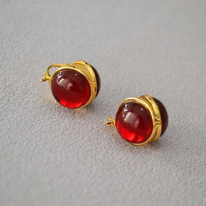 Macro shot of French style vintage gold earrings with deep red translucent glass spheres