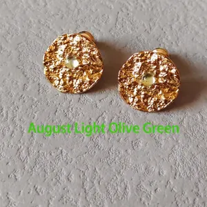 Detailed macro shot of textured gold stud earrings with August light peridot stones