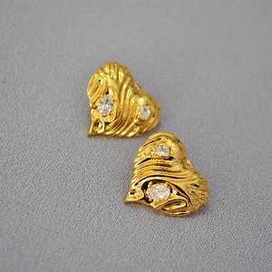Detailed view of vintage gold heart earrings with wavy texture and clear zircon stones