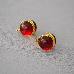 French retro gold earrings with round red translucent beads on grey fabric