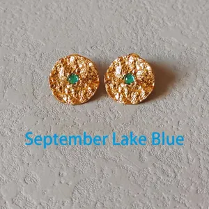 Detail of gold hammer-textured stud earrings with September teal green gemstone centers