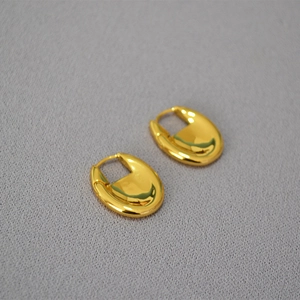 Detailed view of polished thick oval gold-plated hoop earrings with a mirror finish
