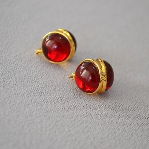 Macro shot of French vintage gold-plated earrings with deep red translucent glass beads