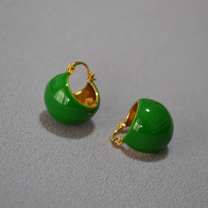 Détail macro de boucles d'oreilles en émail vert avec base en laiton plaqué or