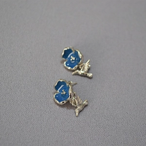 Detail of silver floral earrings with blue enamel petals and dangling hummingbird charms