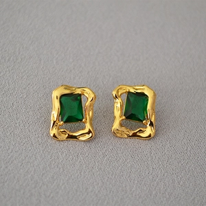 Macro detail of retro brass gold plated earrings with rectangular emerald zircon stones