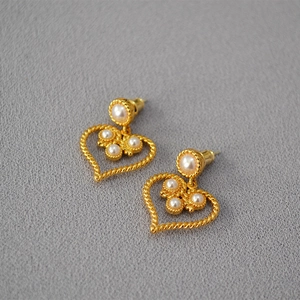 Detailed macro view of French vintage heart earrings with faux pearls and gold rope texture