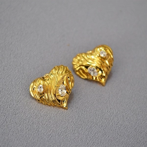 Macro shot of vintage gold heart earrings with twisted texture and zircon stones
