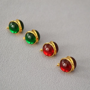 Detailed macro view of vintage red and green glass orb earrings in gold-plated settings