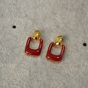 Vintage gold-plated rectangle earrings with deep red enamel coating on grey background