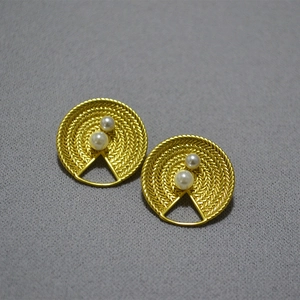 Détail macro de boucles d'oreilles vintage en laiton avec perles et texture tressée