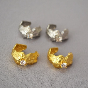 Detail of gold and silver irregular textured earrings with centered cubic zirconia stone