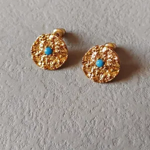 Detail of gold hammered earrings with December turquoise stone in a round setting