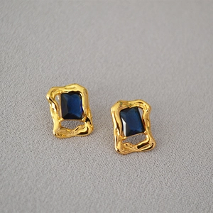 Detail of vintage brass gold earrings with rectangular blue zircon in irregular frames