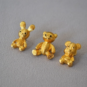 Macro detail of gold animal earrings with textured stripe finish and black bead eyes