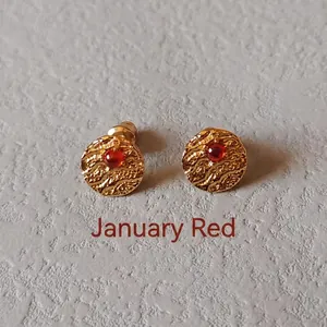 Close-up of golden textured stud earrings featuring a red January birthstone center