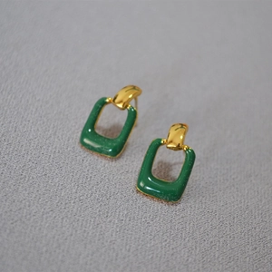 Minimalist rectangular gold earrings with dark green enamel drop on textured background