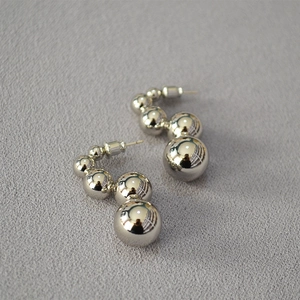 Macro view of silver caterpillar beaded earrings with four polished hollow metal spheres