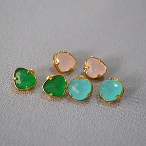 Detail view of heart-shaped jade earrings in pink, green, and blue with gold plating