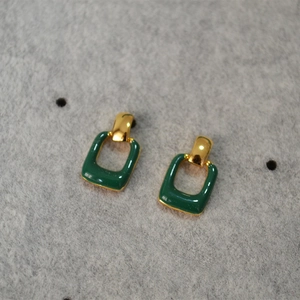 Close-up of vintage geometric dark green enamel earrings with gold metal frame details