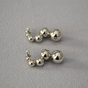 Detailed view of silver J-shape earrings with gradient polished metal hollow beads