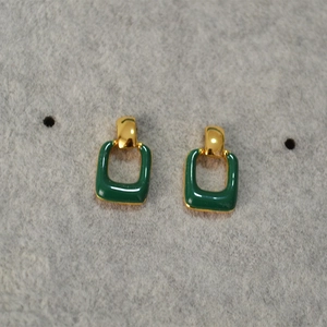 Close-up of geometric square earrings with gold plating and green enamel finish