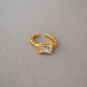 Nahaufnahme eines verstellbaren Goldrings mit rechteckigem Zirkon und Hammerschlag-Optik
