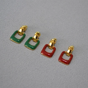 Detail view of geometric square stud earrings in red and green enamel with gold plating