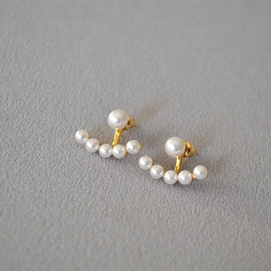 Detailed view of elegant gold curved stud earrings with five white pearls in a fan design