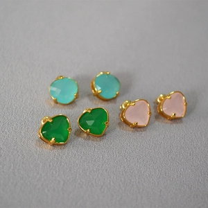 Detailed view of heart-shaped gemstone stud earrings in blue, green, and pink colors