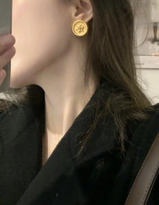 Macro detail of French vintage gold-plated camellia flower disc earrings on model