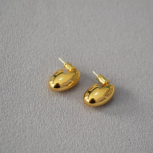 Macro detail of polished gold-plated bean stud earrings with high mirror finish