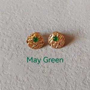 Macro detail of gold textured earring with green gemstone inlay for May birthstone