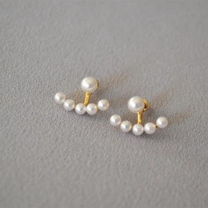 Detailed macro view of elegant pearl ear jackets with gold metal settings on fabric