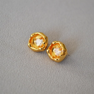 Dettaglio di orecchini a cuore in zircone con texture dorata irregolare e perni in argento 925
