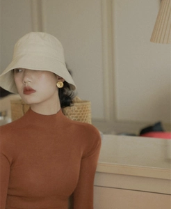 Close-up of a model wearing French vintage camellia gold disc earrings and a sun hat