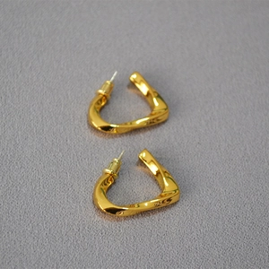 Close-up of twisted gold twisted geometric earrings with polished finish on gray background