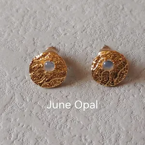 Detail of vintage gold stud earrings with June Opal stone and hammered texture surface