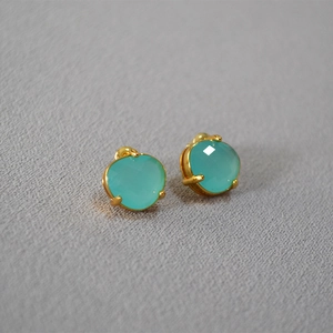 Macro view of mint green faceted stud earrings in gold-plated four-prong settings
