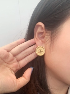 Detailed close-up of a model wearing vintage gold camellia flower disc stud earrings