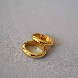 Close-up of two minimalist high-polish gold-plated brass rings overlapping on fabric