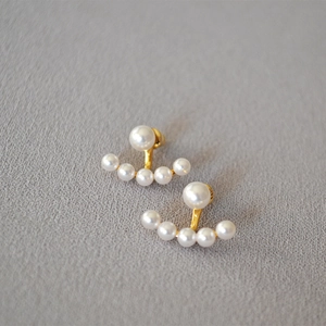 Macro detail of elegant 925 silver needle earrings with suspended pearl arc design