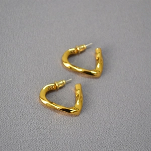 Detail view of twisted geometric gold heart earrings with a unique textured spiral design