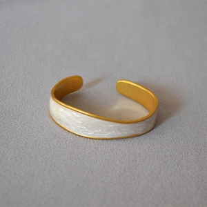 Detail view of gold-plated brass bangle with white marble enamel inlay finish