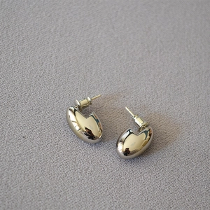 Detail of minimalist egg-shaped silver earrings with high-polished mirror finish